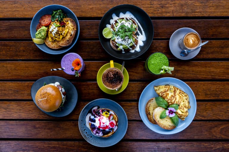 Five different breakfast meals and four different drinks on a table